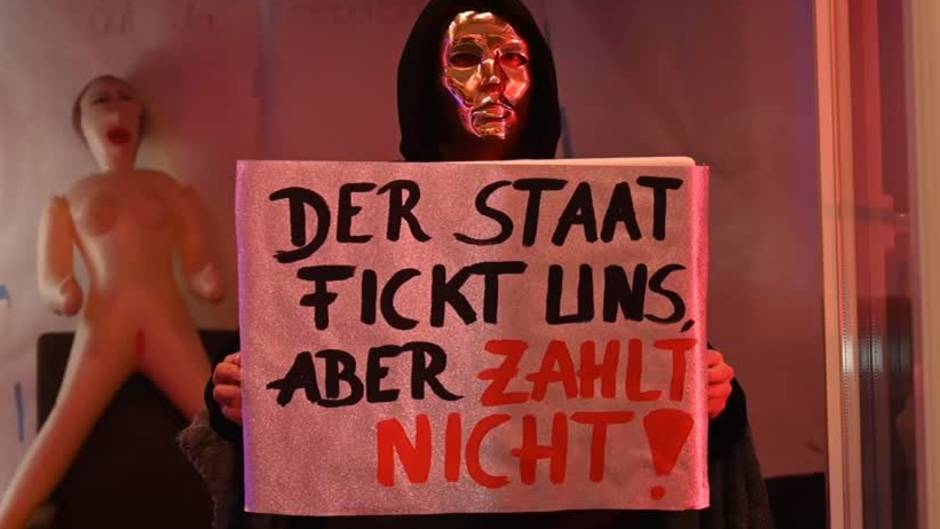 Eine Prostituierte hält in der Herbertstraße ein Schild mit der Aufschrift "Der Staat fickt uns, aber er zahlt nicht".