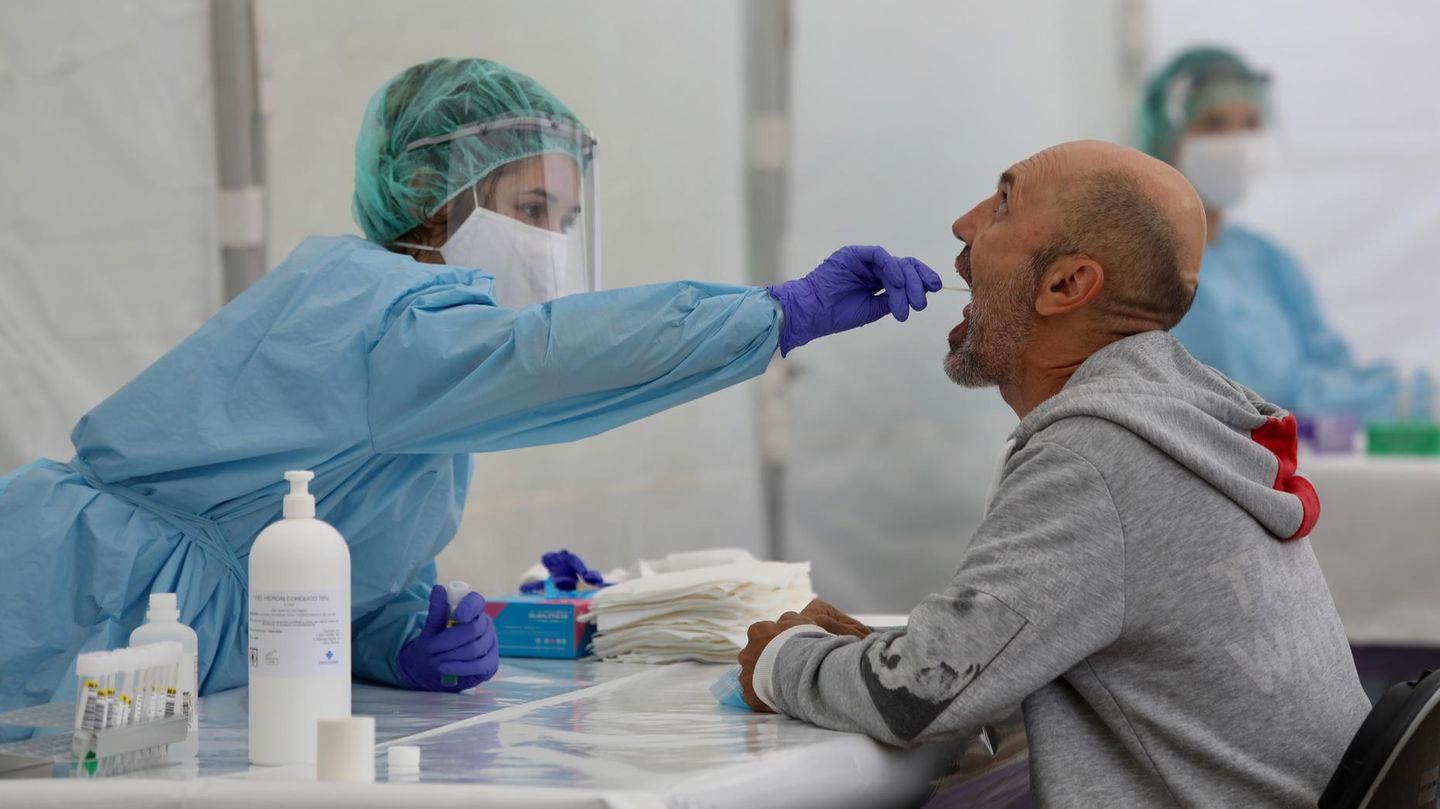 Gesundheitsamts-Mitarbeiterin macht einen Abstrich im Rachen eines Mannes