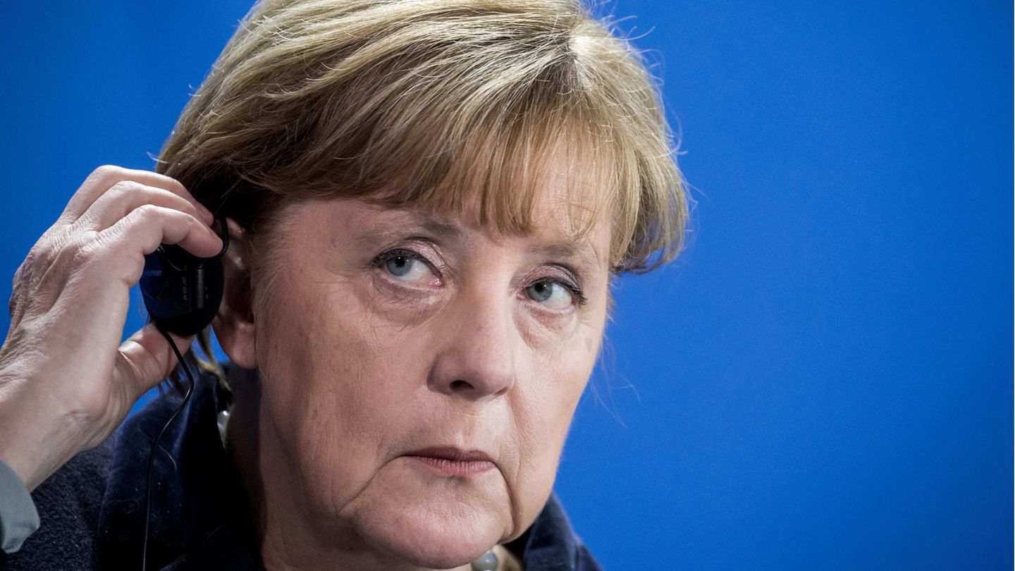 Bundeskanzlerin Angela Merkel hält einen Kopfhörer an ihr Ohr