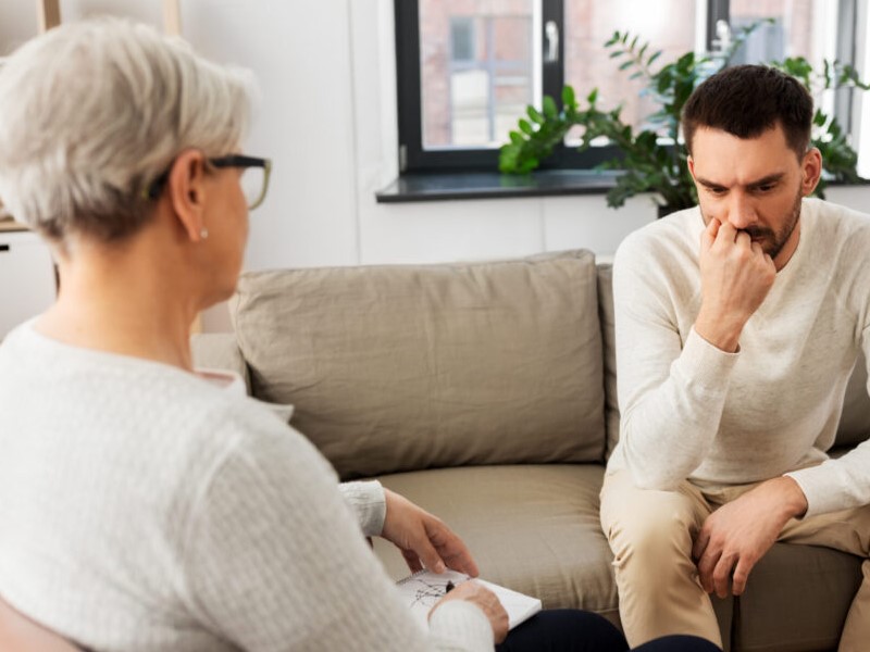 Der Therapeut spricht mit der Person bei Psythotherapie Sitzung über seine Sorgen und Situationen.